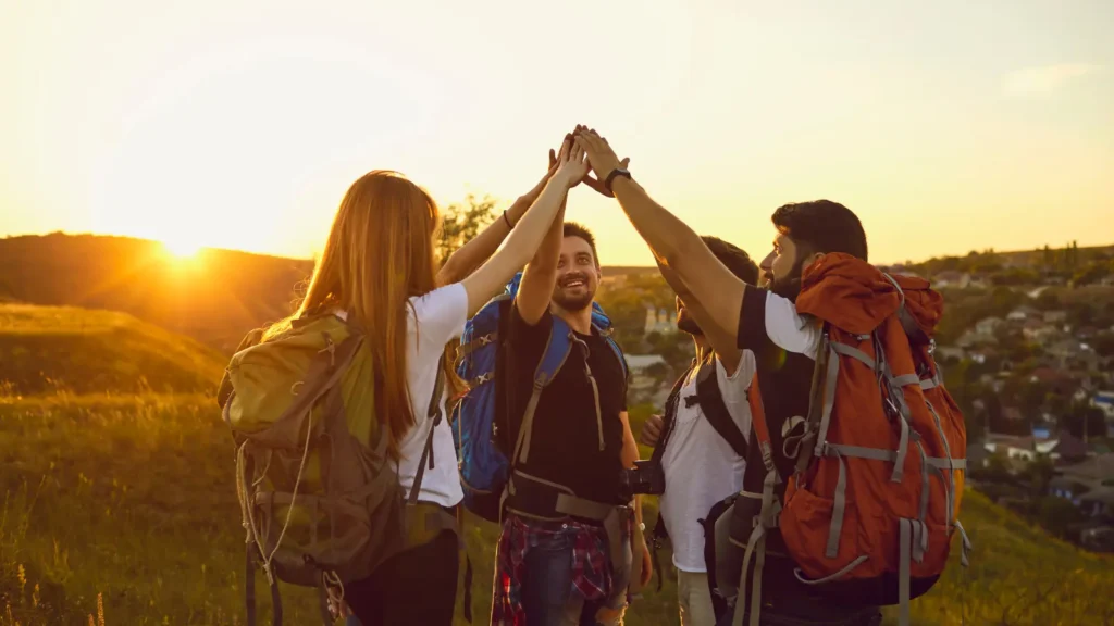 A Group Of People With Backpacks Giving Each Other A High Five